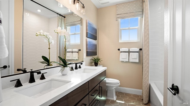 full bathroom with a wealth of natural light, dual bowl vanity, toilet, and tile patterned floors