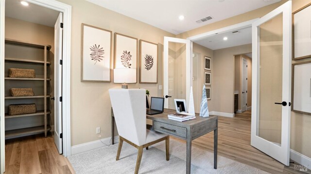 home office with french doors and light hardwood / wood-style flooring