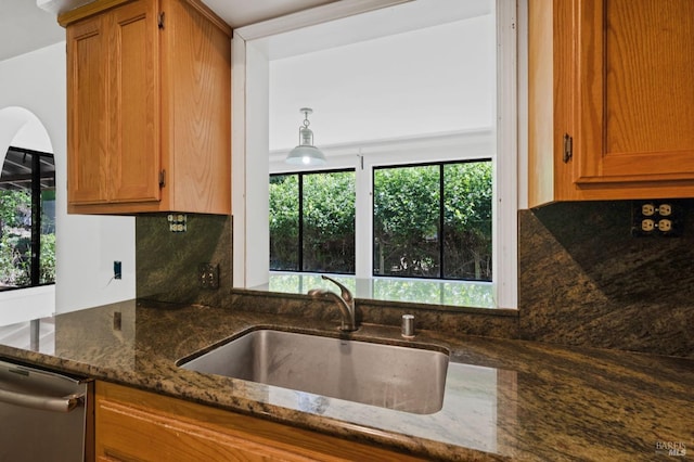 kitchen featuring decorative backsplash, dishwasher, dark stone countertops, and sink