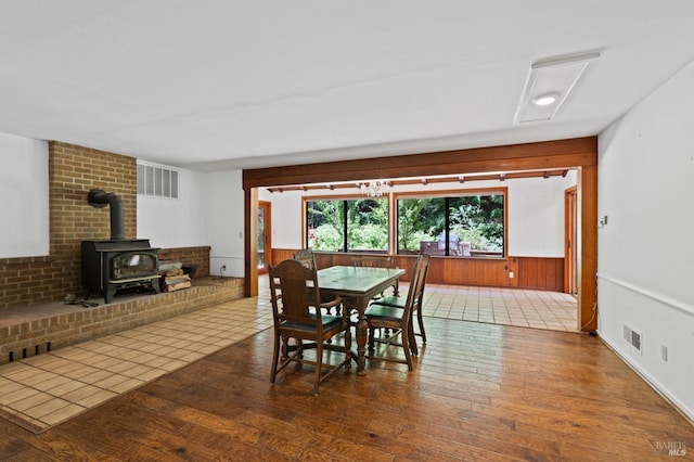 dining room featuring brick wall, a wood stove, and hardwood / wood-style flooring