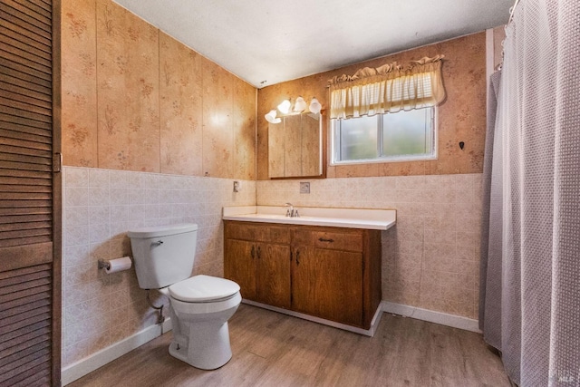 full bathroom with a shower with shower curtain, toilet, vanity, wood finished floors, and tile walls