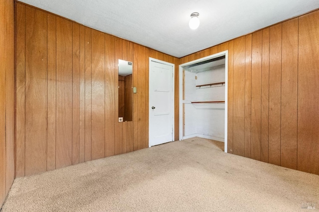 unfurnished bedroom featuring a closet, wood walls, and carpet floors