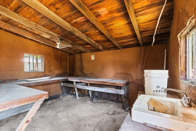 misc room featuring unfinished concrete flooring, lofted ceiling, and a sink