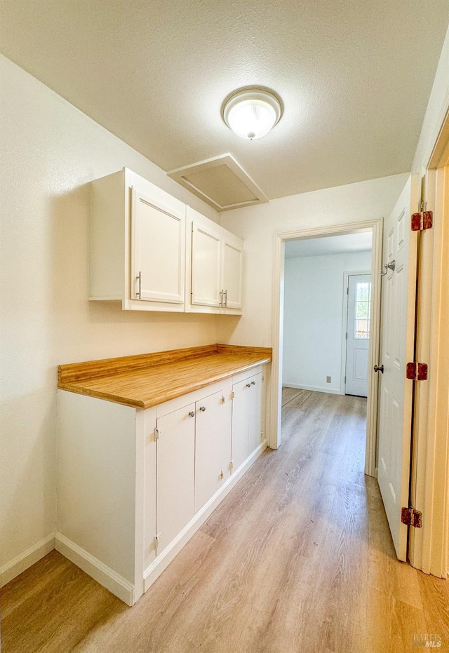 interior space featuring white cabinets, light wood-style flooring, and baseboards