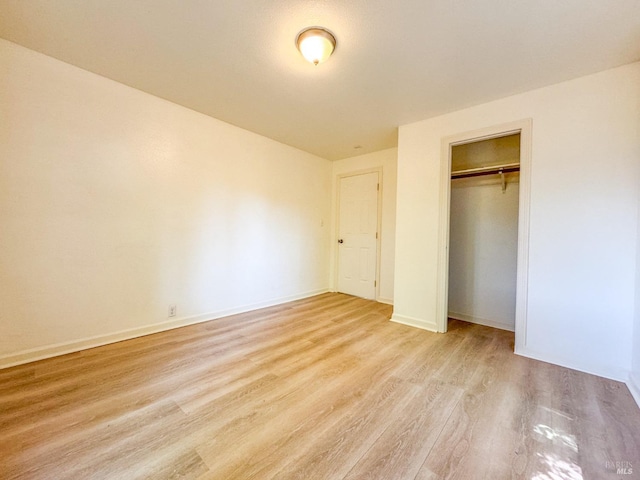 unfurnished bedroom with light wood-type flooring and a closet