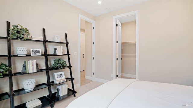 bedroom featuring a spacious closet, a closet, and light carpet