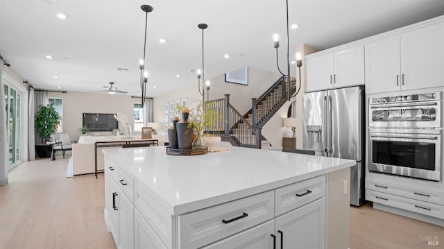 kitchen featuring white cabinets, stainless steel appliances, a kitchen island, and ceiling fan