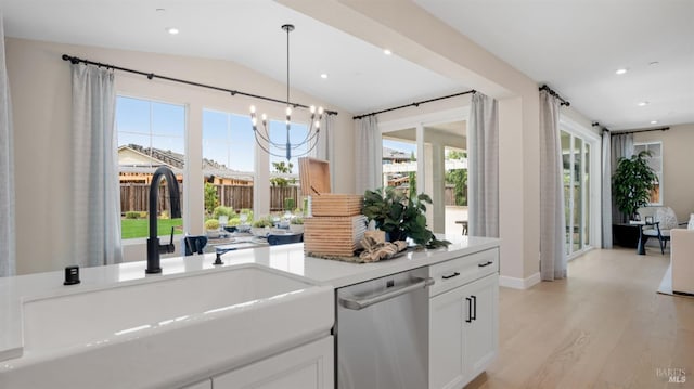 kitchen featuring lofted ceiling, sink, light hardwood / wood-style flooring, stainless steel dishwasher, and white cabinetry