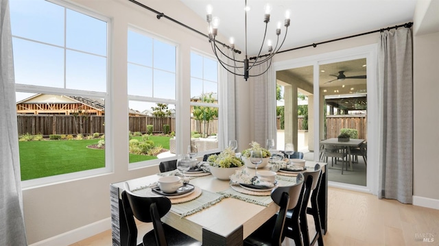 dining room featuring ceiling fan with notable chandelier, light wood-type flooring, and a healthy amount of sunlight