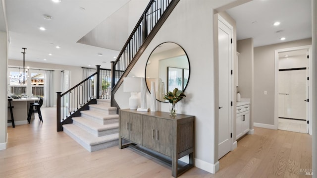 stairs with hardwood / wood-style floors and an inviting chandelier