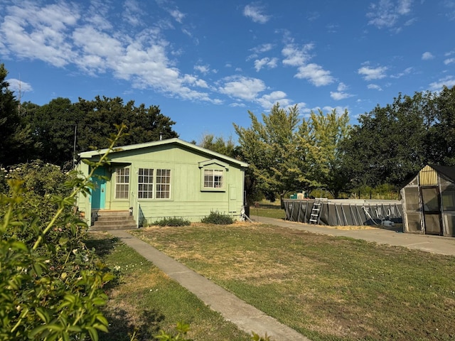 view of home's exterior with a lawn, an outdoor structure, and a greenhouse