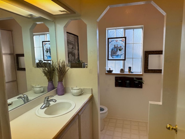 bathroom with toilet, vanity, and tile patterned floors