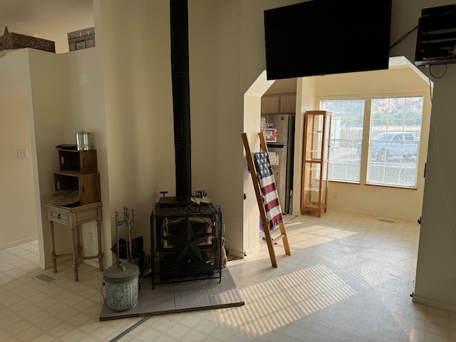 living room with a towering ceiling and a wood stove