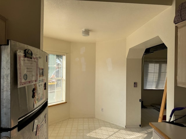 kitchen with freestanding refrigerator, baseboards, and light floors