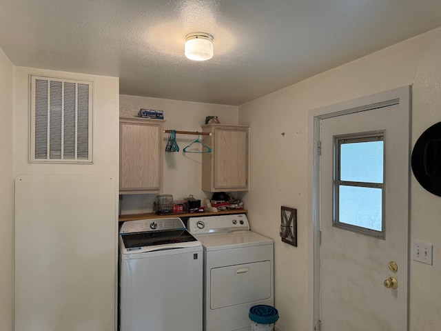 laundry area featuring separate washer and dryer, cabinet space, a textured ceiling, and visible vents