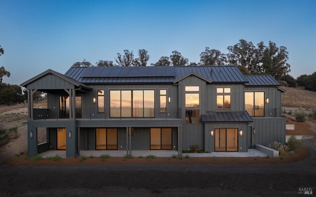 rear view of house featuring solar panels and a balcony