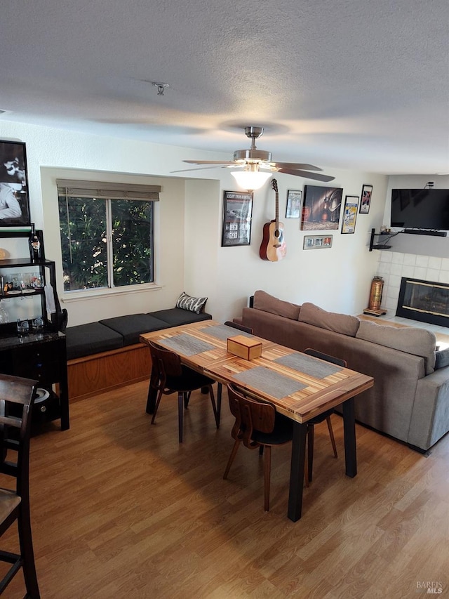 1142 Pear Tree Ln, Napa, CA 94558 - dining area featuring light wood-style floors, a ceiling fan, a textured ceiling, and a tiled fireplace