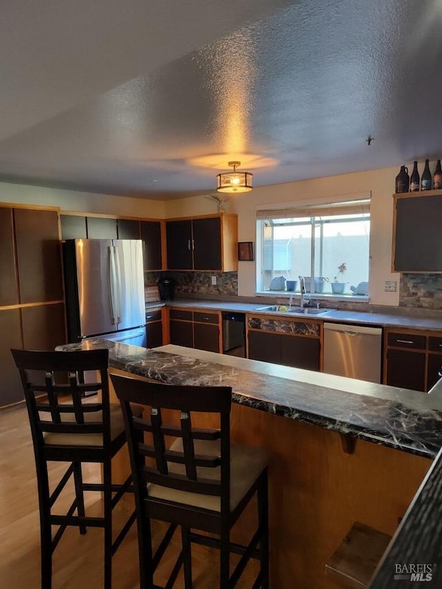 1142 Pear Tree Ln, Napa, CA 94558 - kitchen with appliances with stainless steel finishes, a sink, dark countertops, a breakfast bar area, and backsplash