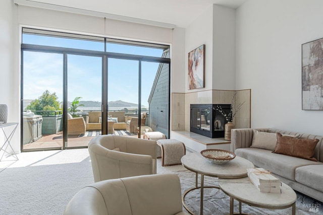 living room with a tile fireplace, a mountain view, and light carpet