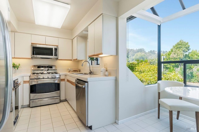 kitchen with sink, white cabinets, light tile patterned floors, and appliances with stainless steel finishes