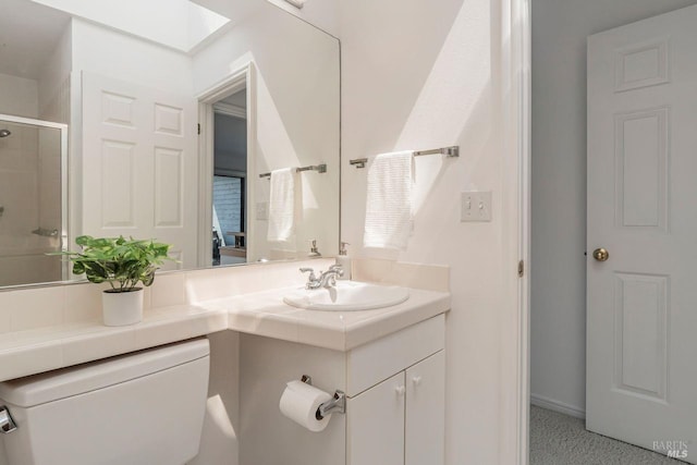 bathroom featuring walk in shower, a skylight, vanity, and toilet