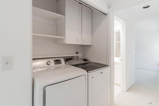 washroom featuring cabinets and washer and clothes dryer