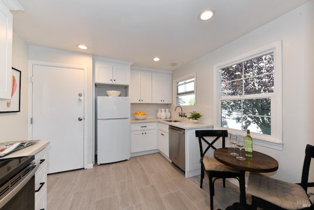 kitchen featuring backsplash, stainless steel appliances, sink, and white cabinets