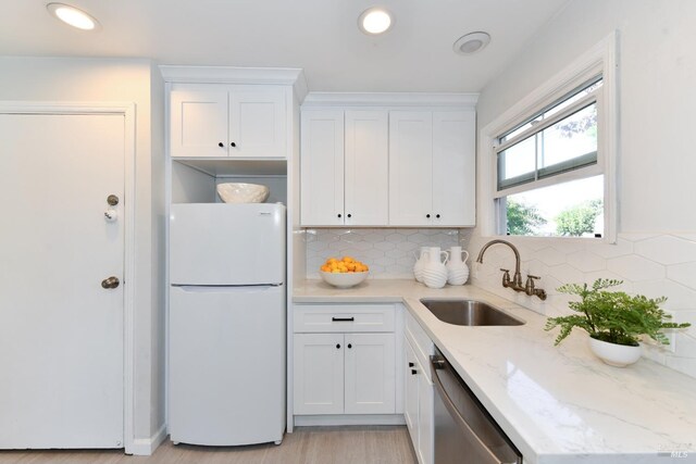 kitchen with sink, dishwasher, white cabinetry, light stone counters, and white fridge