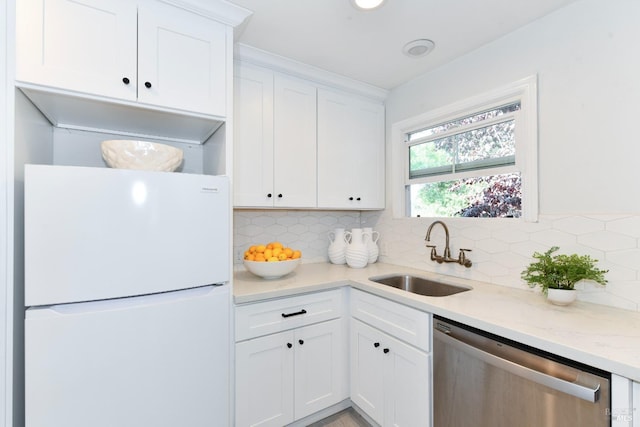 kitchen with sink, dishwasher, white cabinetry, white refrigerator, and light stone countertops