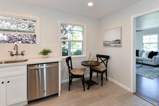 kitchen featuring white cabinetry, dishwasher, sink, and tasteful backsplash