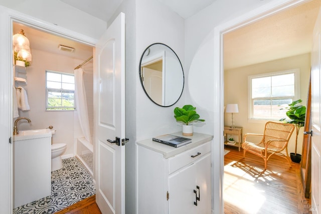 full bathroom with shower / bath combination with curtain, a healthy amount of sunlight, toilet, and vanity