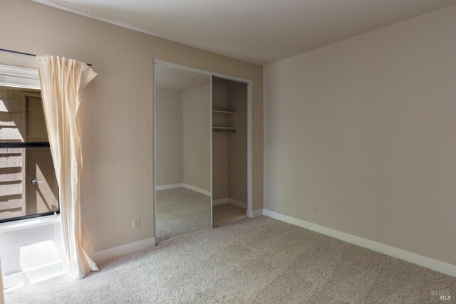 unfurnished bedroom featuring a closet and light colored carpet