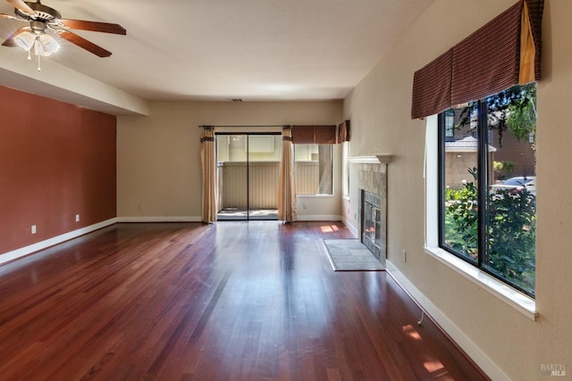 unfurnished living room with wood-type flooring, a tiled fireplace, and ceiling fan