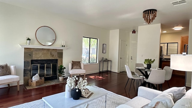 living area featuring visible vents, baseboards, wood finished floors, and a tiled fireplace