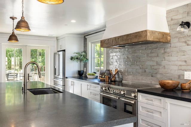 kitchen featuring sink, custom exhaust hood, white cabinetry, high quality appliances, and pendant lighting