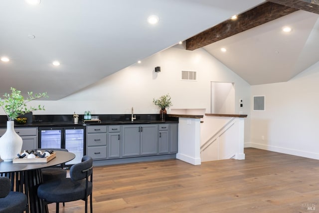 kitchen with sink, gray cabinets, lofted ceiling with beams, and light wood-type flooring