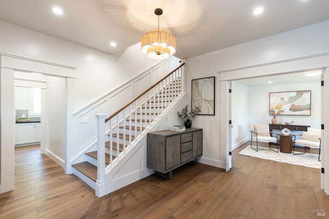 stairs with an inviting chandelier and wood-type flooring