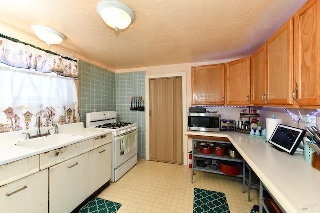 kitchen with tile walls, sink, a textured ceiling, and white gas range