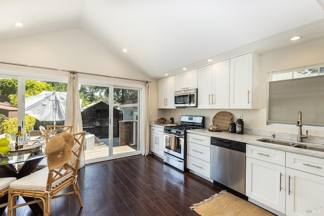 kitchen featuring dark wood-type flooring, white cabinetry, vaulted ceiling, and stainless steel appliances