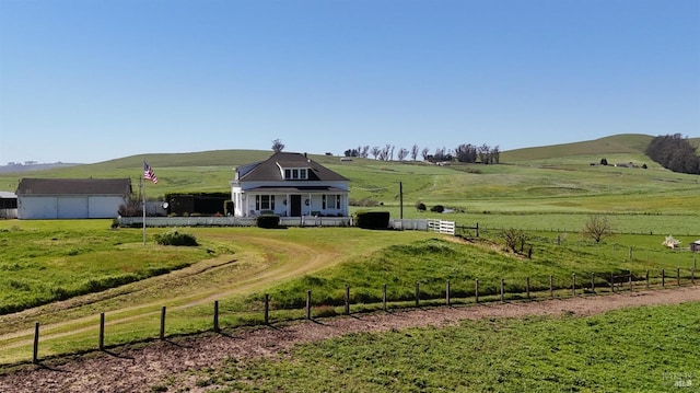 view of front of house featuring fence, a rural view, a front lawn, and covered porch