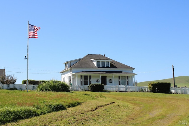 view of front of property with a porch, a front yard, fence, and a shingled roof