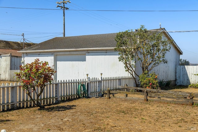 view of home's exterior featuring fence and a shingled roof