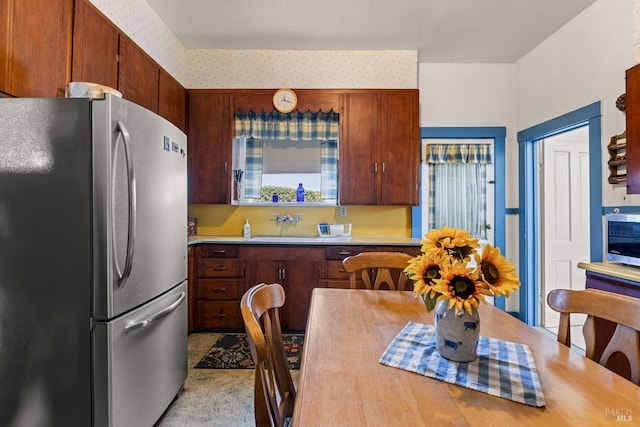 kitchen featuring light countertops, freestanding refrigerator, wallpapered walls, and a sink