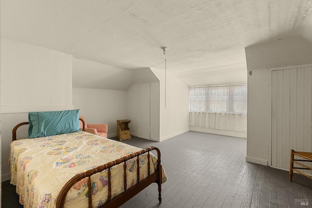 bedroom with hardwood / wood-style flooring, lofted ceiling, and baseboards