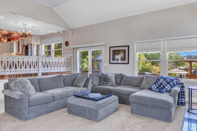 living room featuring an inviting chandelier, light hardwood / wood-style floors, lofted ceiling, and track lighting