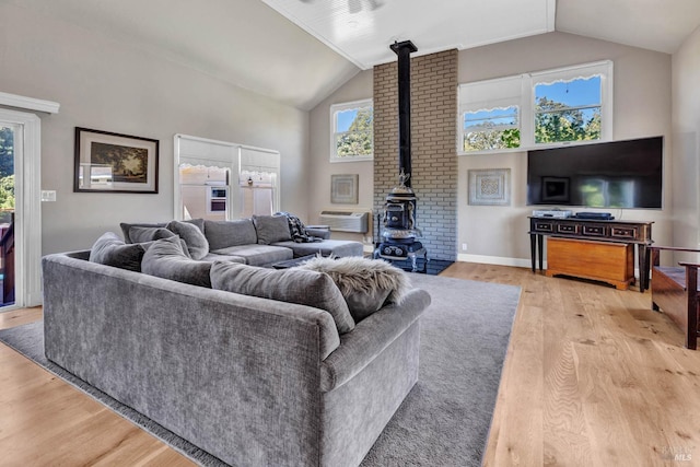 living room featuring a wood stove, light hardwood / wood-style floors, and vaulted ceiling