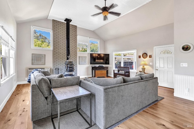 living room featuring brick wall, ceiling fan, wood-type flooring, and a wood stove