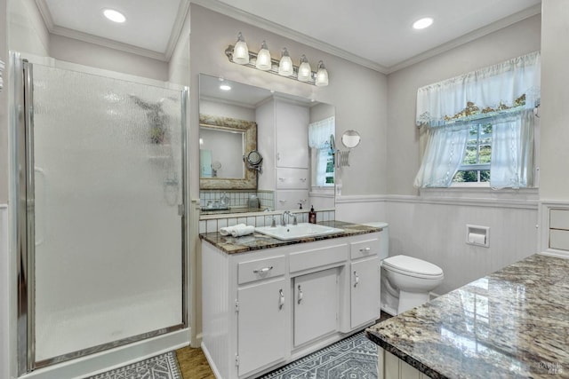 bathroom with a shower with shower door, vanity, ornamental molding, and toilet