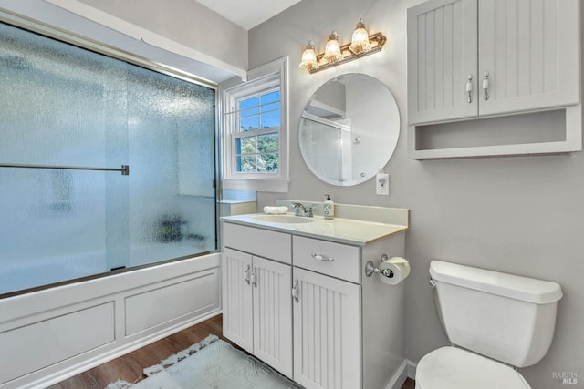 full bathroom featuring hardwood / wood-style flooring, toilet, shower / bath combination with glass door, and vanity