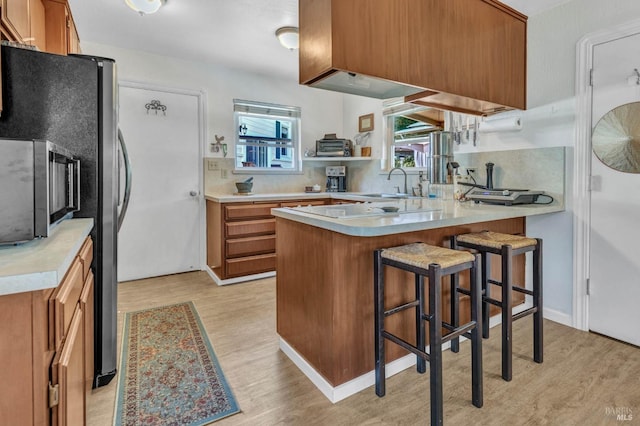 kitchen featuring backsplash, a breakfast bar, light wood-type flooring, and kitchen peninsula